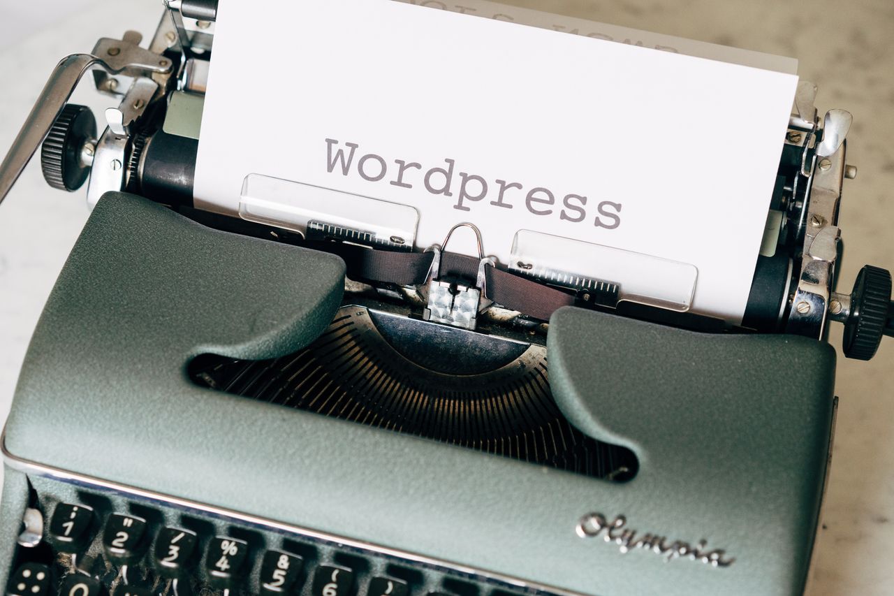 Vue rapprochée d'une machine à écrire vintage avec une feuille affichant WordPress dans un style rétro.